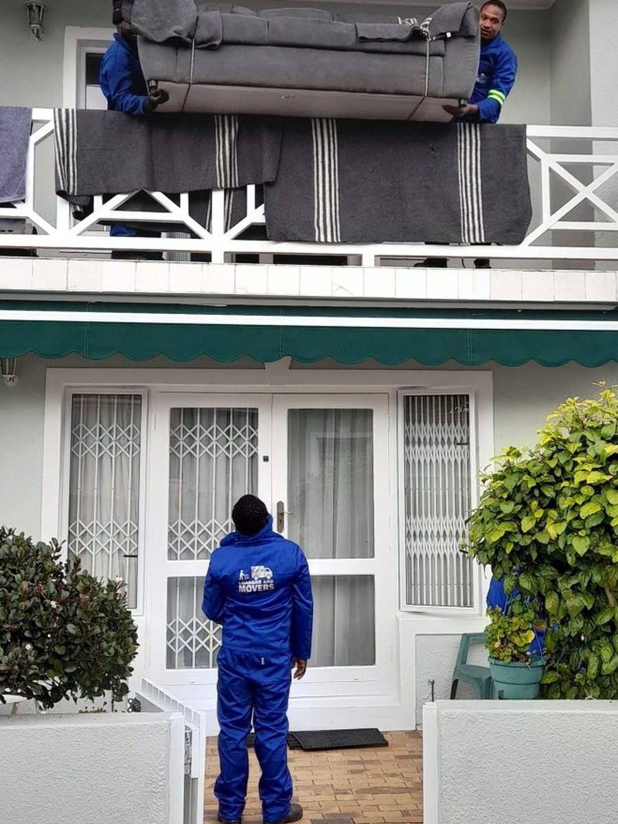 Moving team carrying a large couch from a balcony
